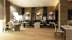 A spacious dining area with multiple tables and chairs, framed artwork on the walls, and a modern interior design. - Hotel Grand Imawan (Makassar)