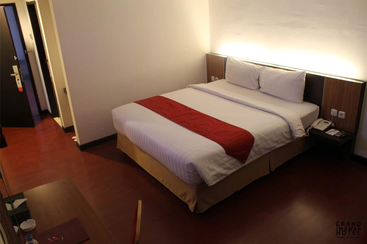 Una habitación de hotel con cama, mesita de noche y un velador.