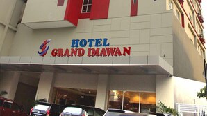 A multi-story hotel building with a prominent red vertical stripe and the name "HOTEL GRAND IMAWAN" on the facade. - Hotel Grand Imawan (Makassar)