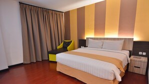 A hotel room with a large bed, a bedside table, a chair, and a curtain. - Hotel Grand Imawan (Makassar)