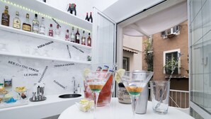 Zona de bar con una encimera blanca, diferentes botellas de licor y dos vasos de martini.