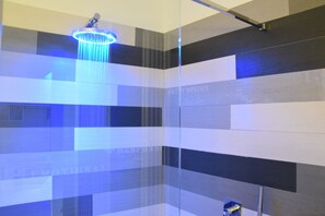 A modern shower with a glass enclosure and a blue-lit showerhead. - Design&Art Pie' (Rome)
