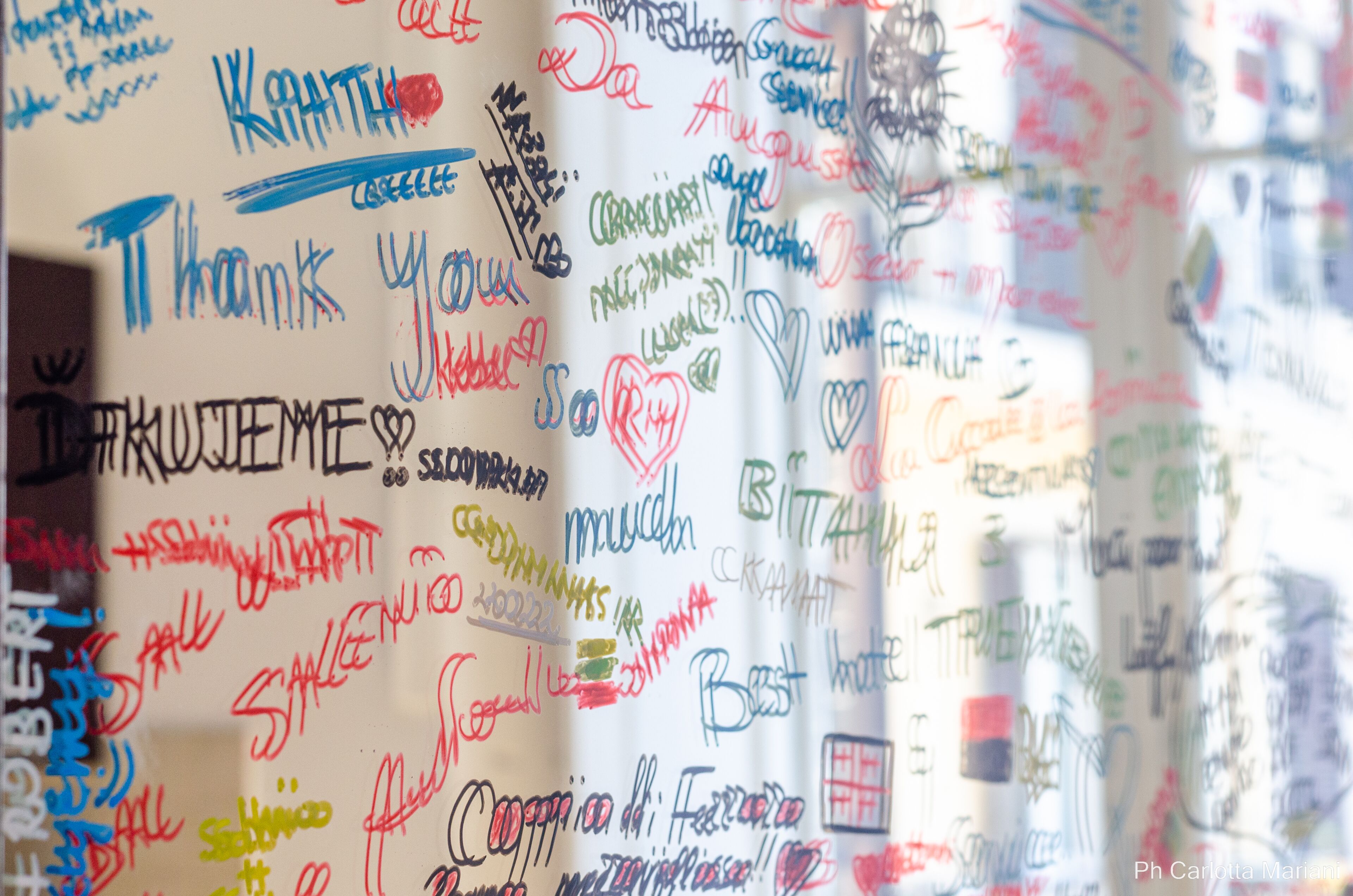 A wall covered with various handwritten messages and drawings, including words like "Thank You" and "Best Wishes."