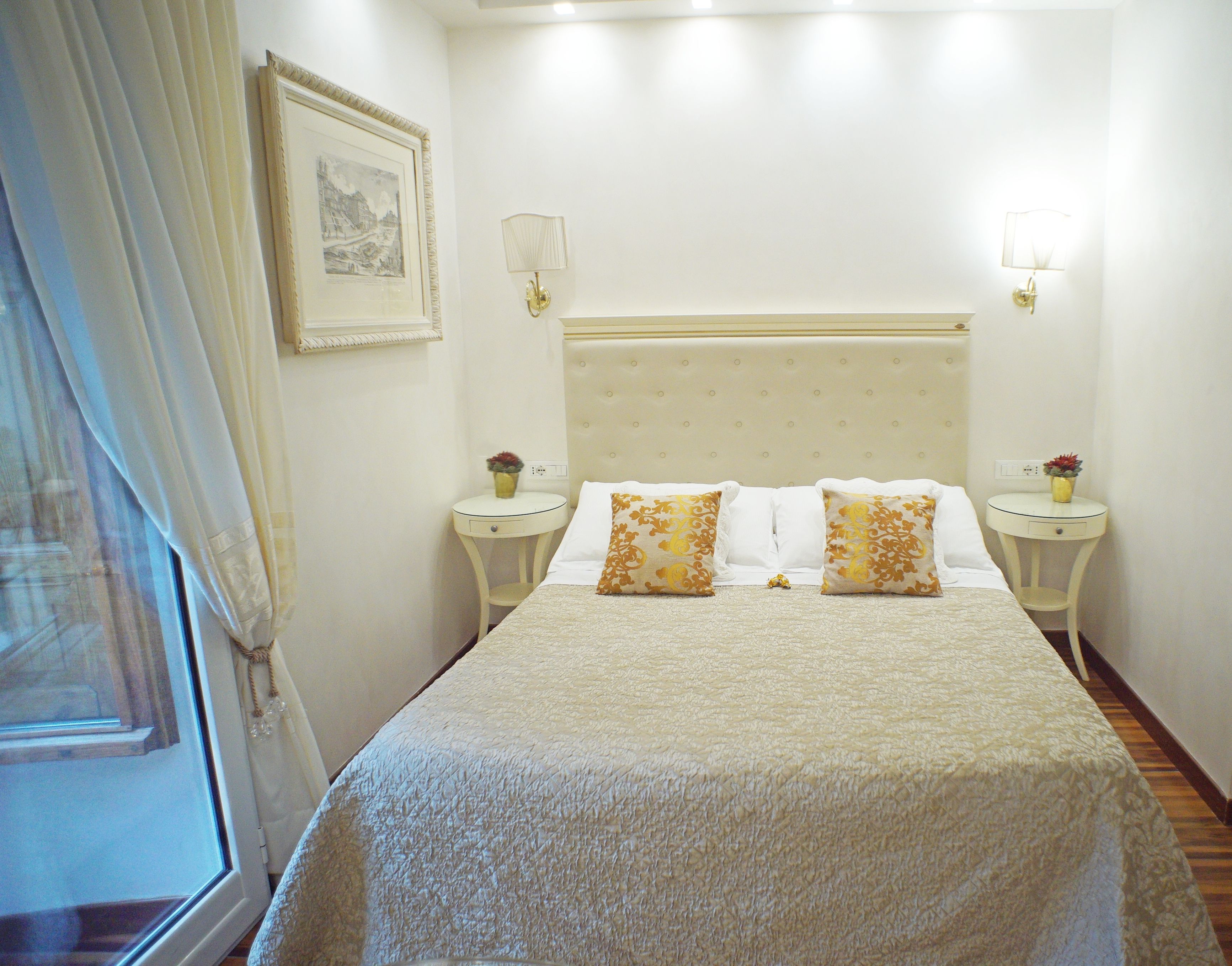 A neatly arranged bedroom with a large bed, two bedside tables, and a framed picture on the wall.