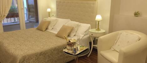 A hotel room with a bed, a chair, a bedside table with a lamp, and a view of the outside.