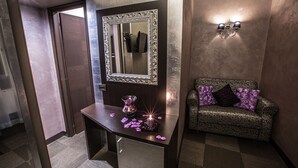 A modern bathroom with a large mirror, a vanity with a sink, and a patterned sofa. - Hotel Romano (Rome)