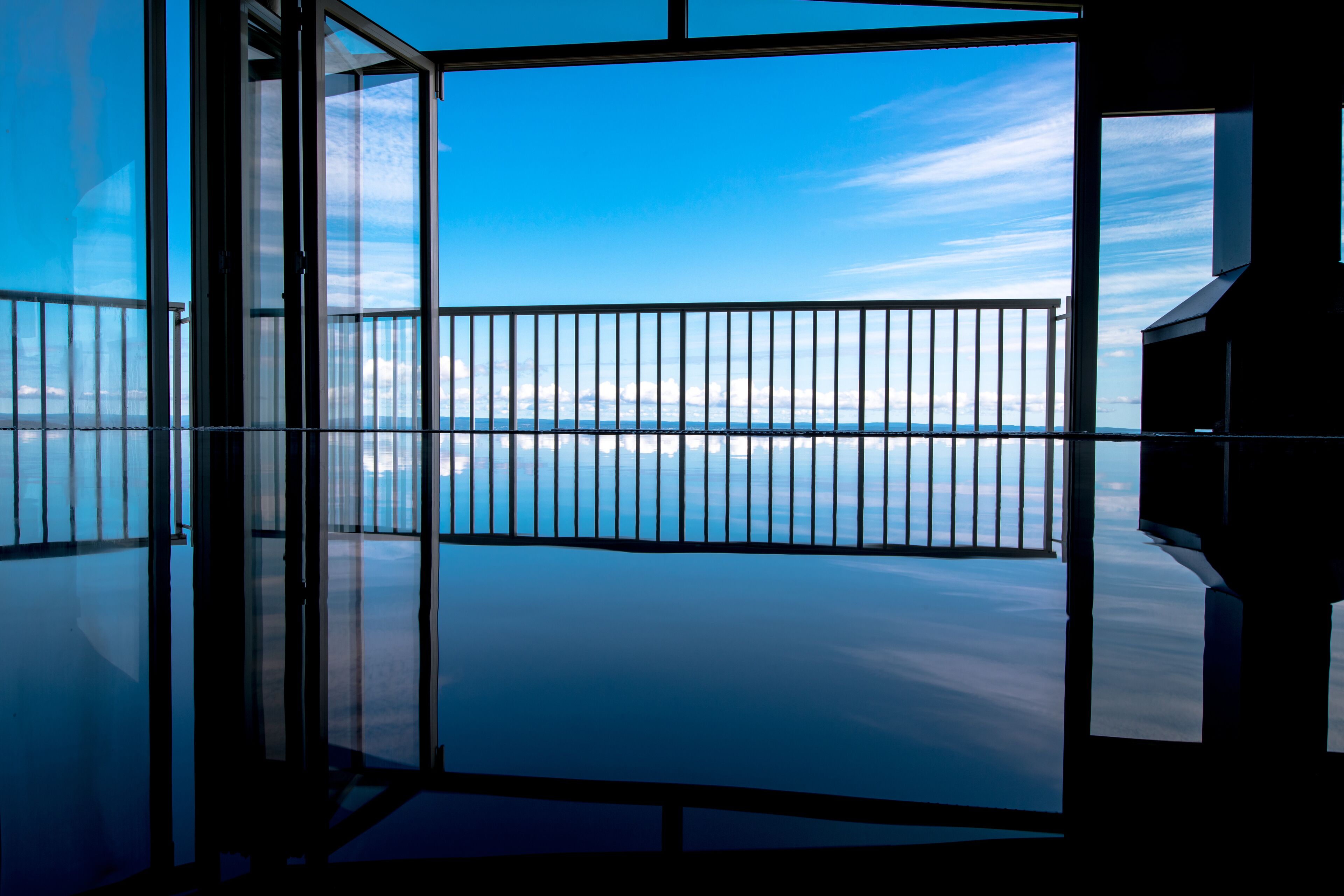 A modern interior with a large glass window offering a view of the sea and sky.