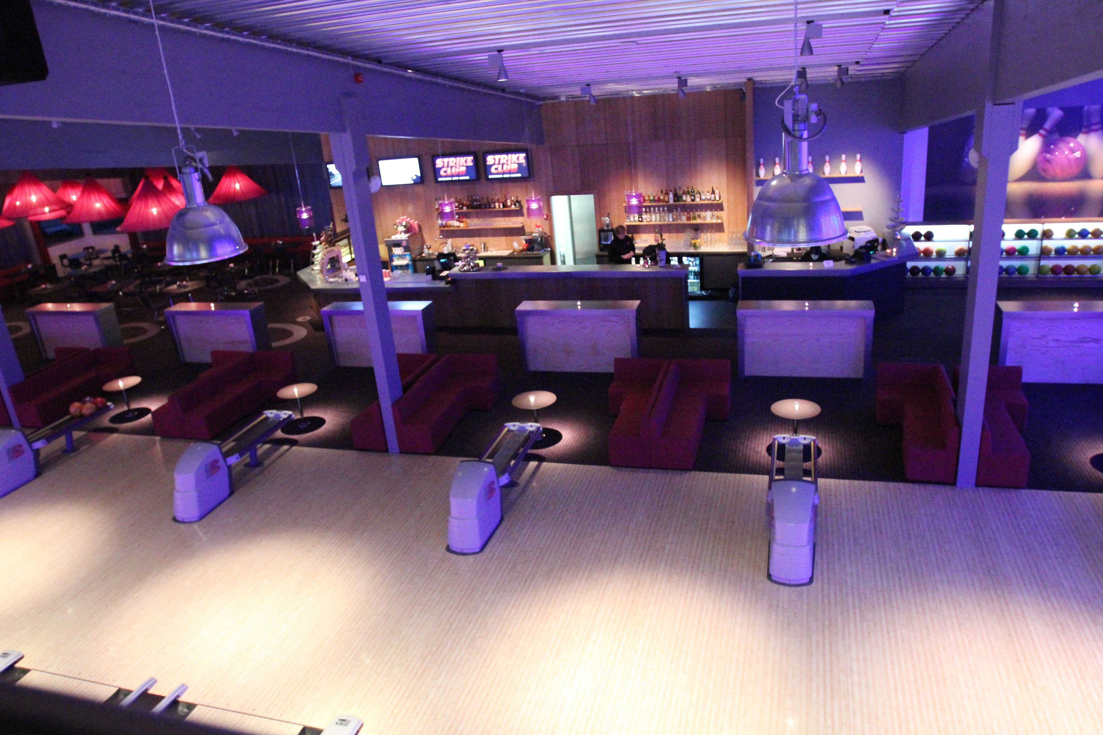 A bowling alley with seating areas, a bar, and bowling lanes.