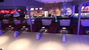 A bowling alley with seating areas, a bar, and bowling lanes.