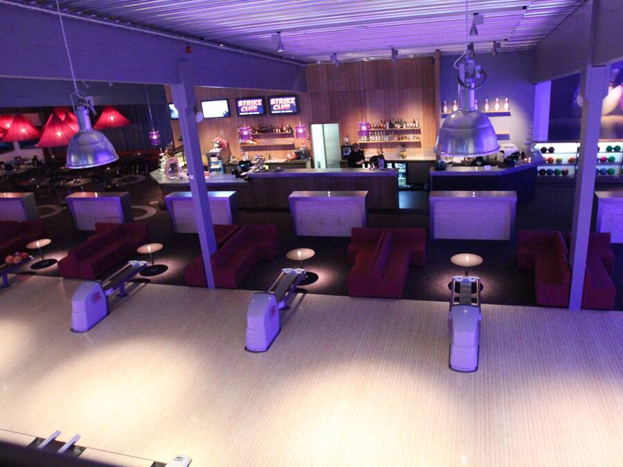 A bowling alley with seating areas, a bar, and bowling lanes.
