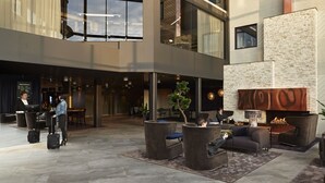 Un vestíbulo amplio con diseño moderno, que incluye una zona de estar con sofás y sillones, una chimenea y un ventanal grande con vistas al interior.