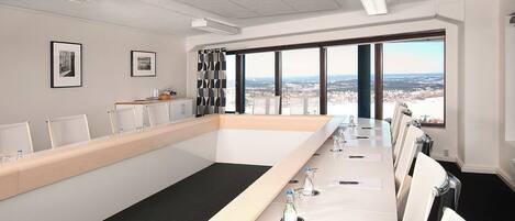 A conference room with a long table, chairs, and a city view through large windows.