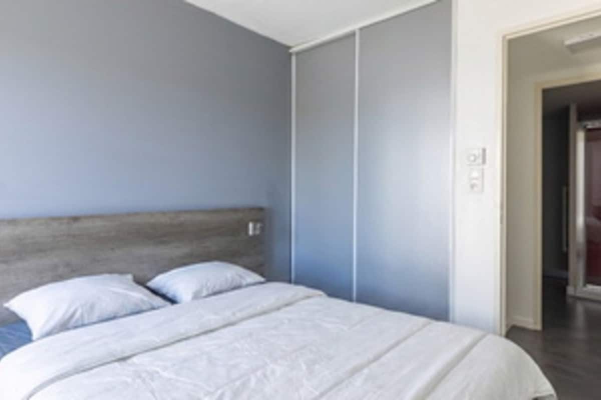 Une chambre à coucher comprenant un lit, une armoire et une porte donnant sur une autre pièce.