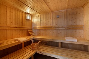 Un sauna avec des bancs en bois, un seau en bois et une serviette posée sur l’un des bancs.