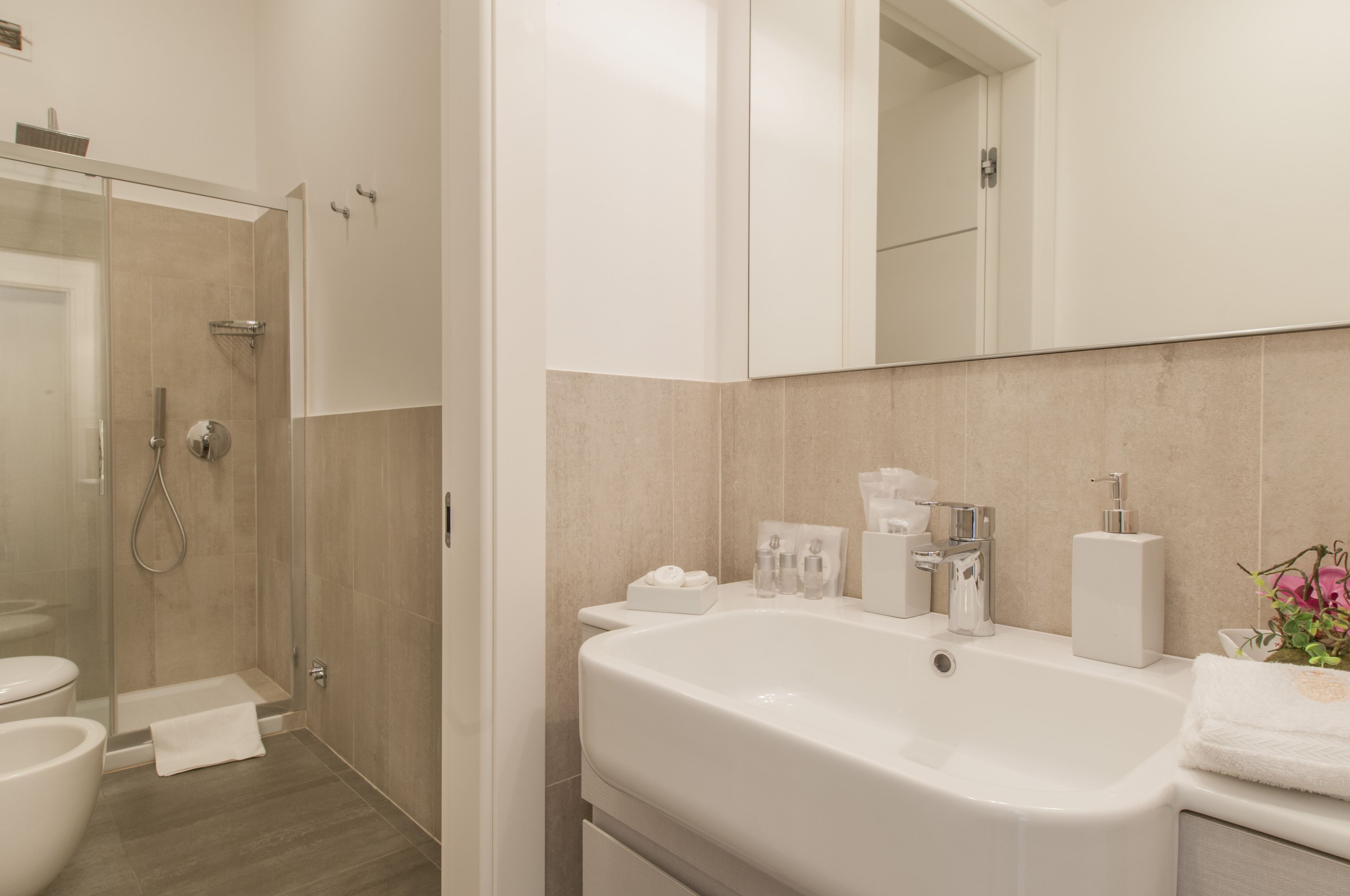 A modern bathroom with a glass-enclosed shower, a large white sink, and a mirror above the sink.