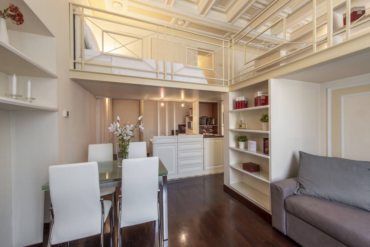 A modern interior with a dining area, a sofa, and a staircase leading to an upper level.