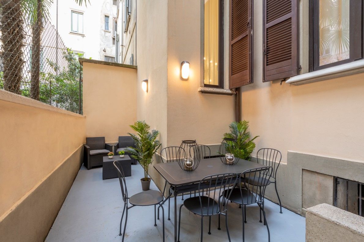 An outdoor patio with a table and chairs, potted plants, and a seating area.
