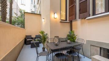 An outdoor patio with a table and chairs, potted plants, and a seating area.