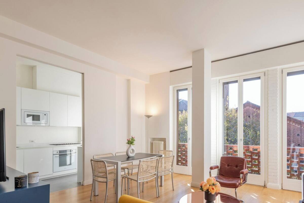 A modern apartment with a kitchen, dining area, and a balcony with a city view.