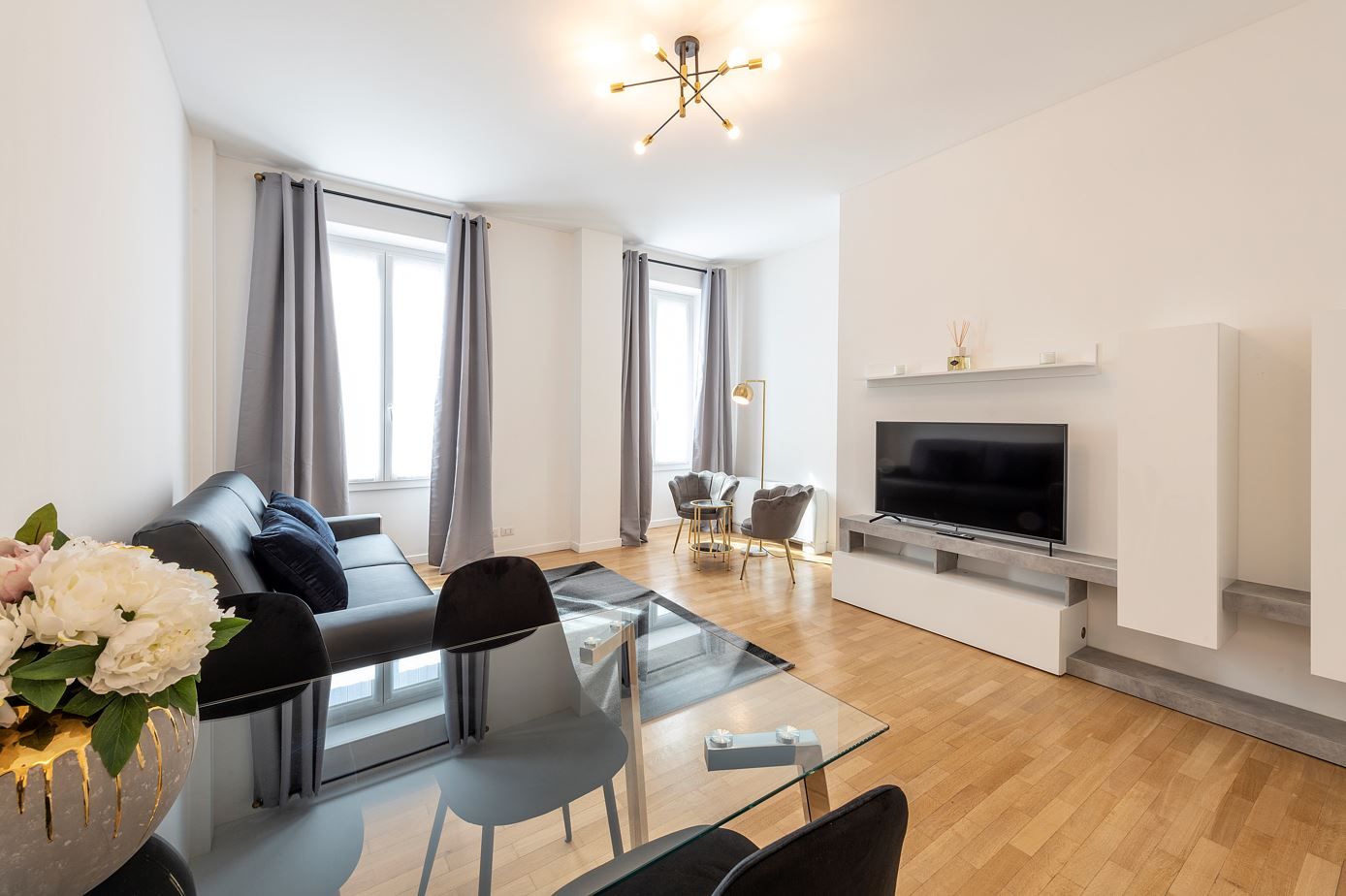 Ein modernes Wohnzimmer mit einer Couch, einem Glastisch und einem Flachbildfernseher.