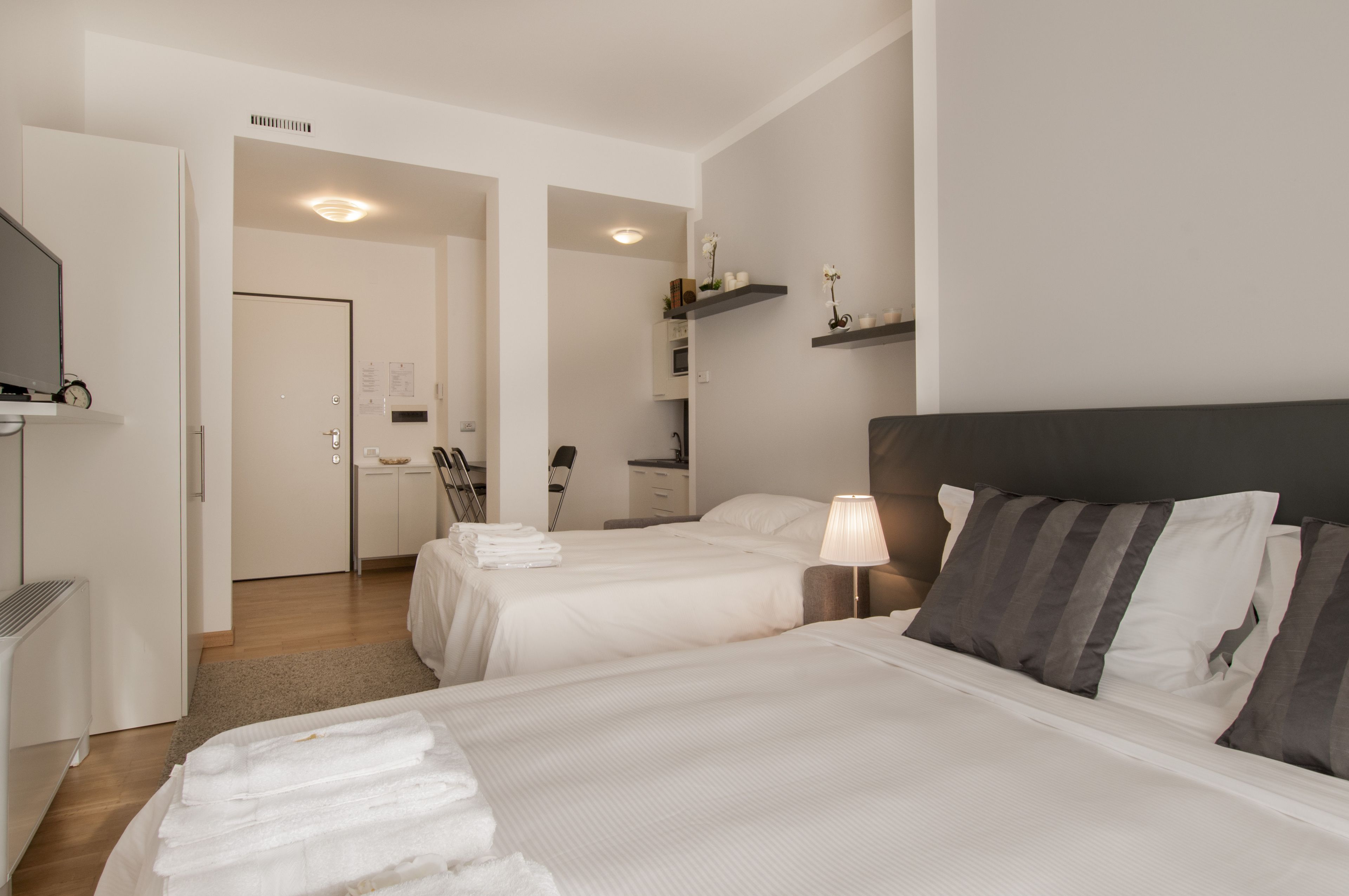 A hotel room with two beds, a desk, and a chair.