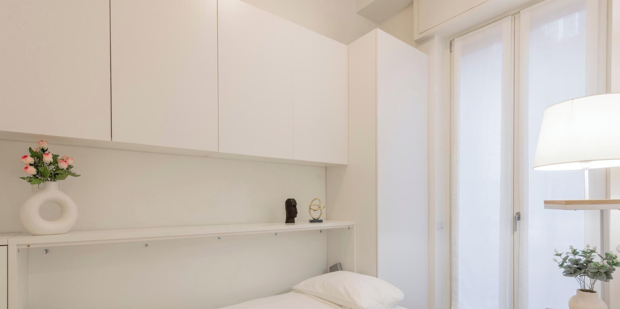 Ein Schlafzimmer mit einem Bett, einem Nachttisch, einer Ablage mit Dekoration und einer Tür.