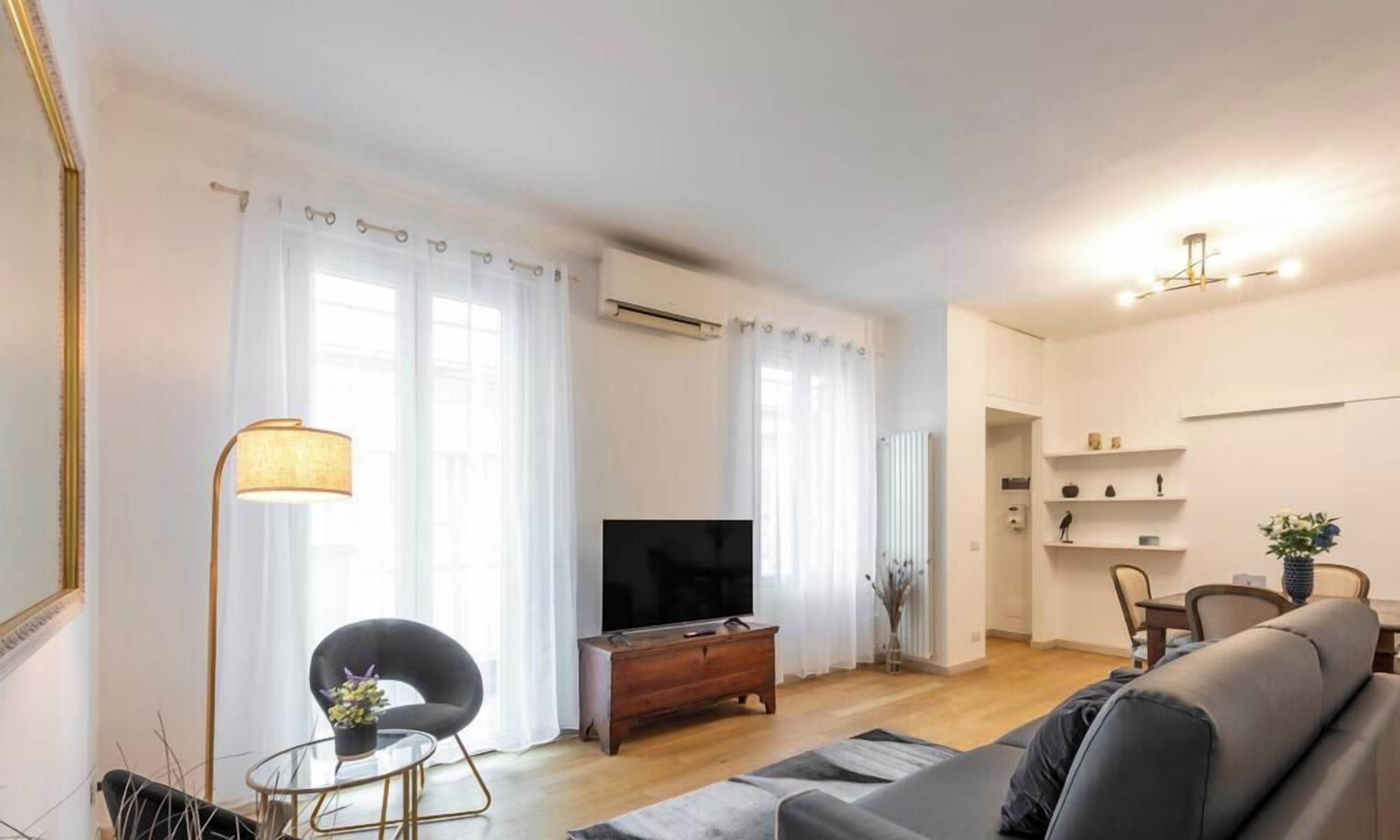 Ett modernt vardagsrum med en platt-TV, en soffa, ett soffbord och en fåtölj.