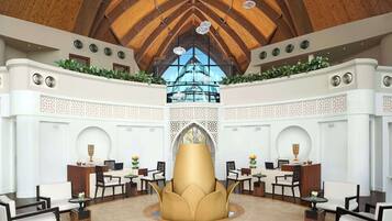 A spacious lobby with a high wooden ceiling, a central decorative fountain, and a view through a large window.