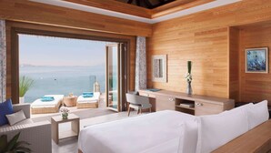 Een moderne hotelkamer met een groot bed, een bureau en uitzicht op zee.