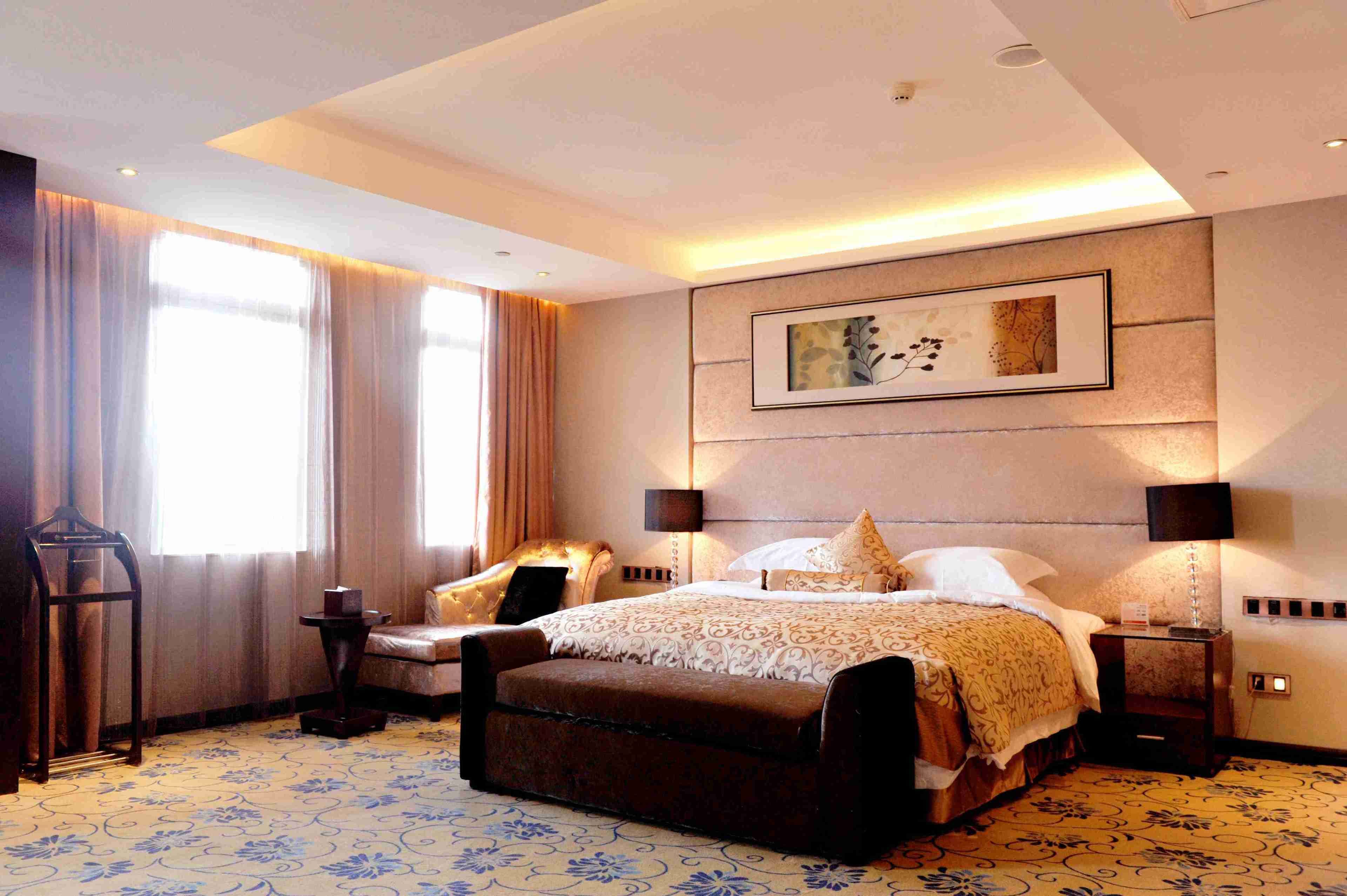 A spacious hotel room with a large bed, a sitting area, and a view of the outdoors.