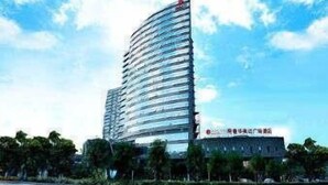 Ein modernes Hochhaus-Hotel mit geschwungener Fassade, mehreren Balkonen und einem markanten Eingang mit Beschilderung.