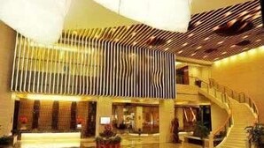 Eine moderne Hotellobby mit einer zentralen Treppe, einem Empfangsbereich und einem großzügigen Atrium.