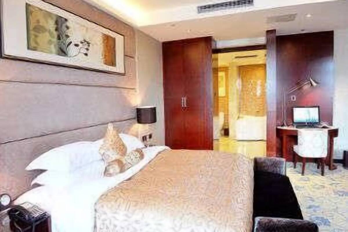 Una habitación de hotel con cama, mesita de noche, lámpara y escritorio con computadora.