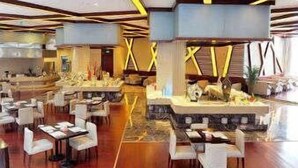 Ein geräumiges Restaurant mit mehreren Tischen und Stühlen, einem zentralen Dekorationsbereich mit einer Statue und einem modernen Deckenstil.