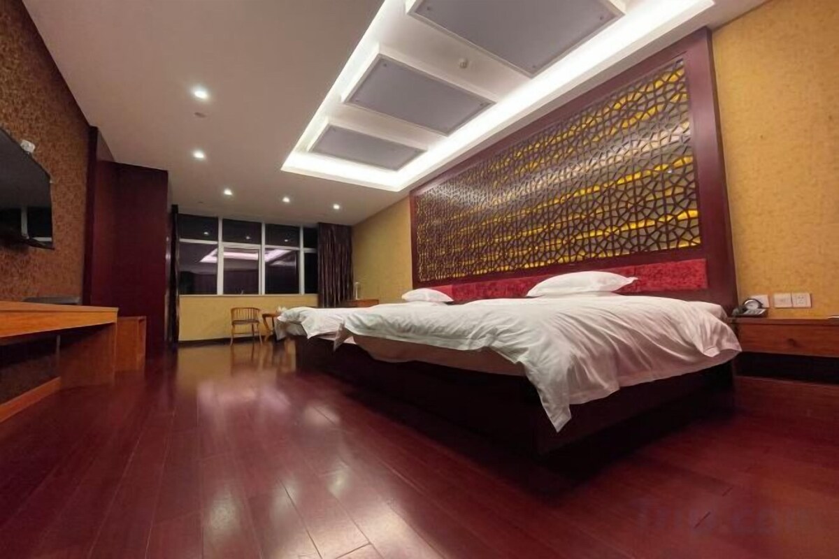 A hotel room with a large bed, a desk, and a chair.