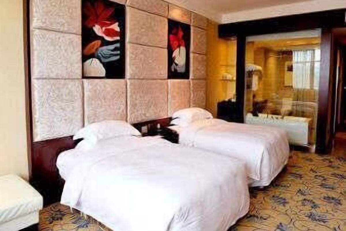 Habitación de hotel con dos camas, un espejo grande y una alfombra estampada.