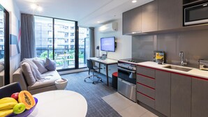 A modern kitchen with a built-in microwave, a sink, and a dining area with a table and a bowl of fruit. - MainStay Suites Abbotsford (Abbotsford)