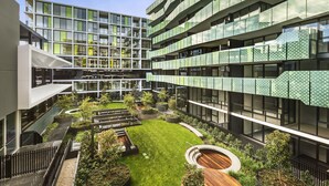 A modern building with multiple floors, large windows, and a central courtyard with greenery and seating areas. - MainStay Suites Abbotsford (Abbotsford)