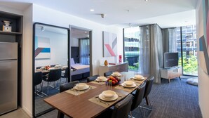 A modern hotel room with a dining area, a bed, a TV, and a view of the city. - MainStay Suites Abbotsford (Abbotsford)