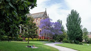 A well-maintained garden with a pathway leading to a historic building with red brick walls and a clock tower. - MainStay Suites Abbotsford (Abbotsford)