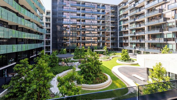 A modern apartment building with multiple balconies, a central courtyard with greenery, and a curved driveway. - MainStay Suites Abbotsford (Abbotsford)