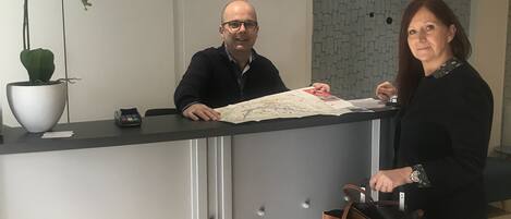 Un mostrador de recepción con un mapa, una orquídea en maceta y un reloj en la pared.