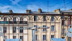 A row of residential buildings with balconies, a metal fence, and a clear blue sky. - Hotel De Venise (Paris)