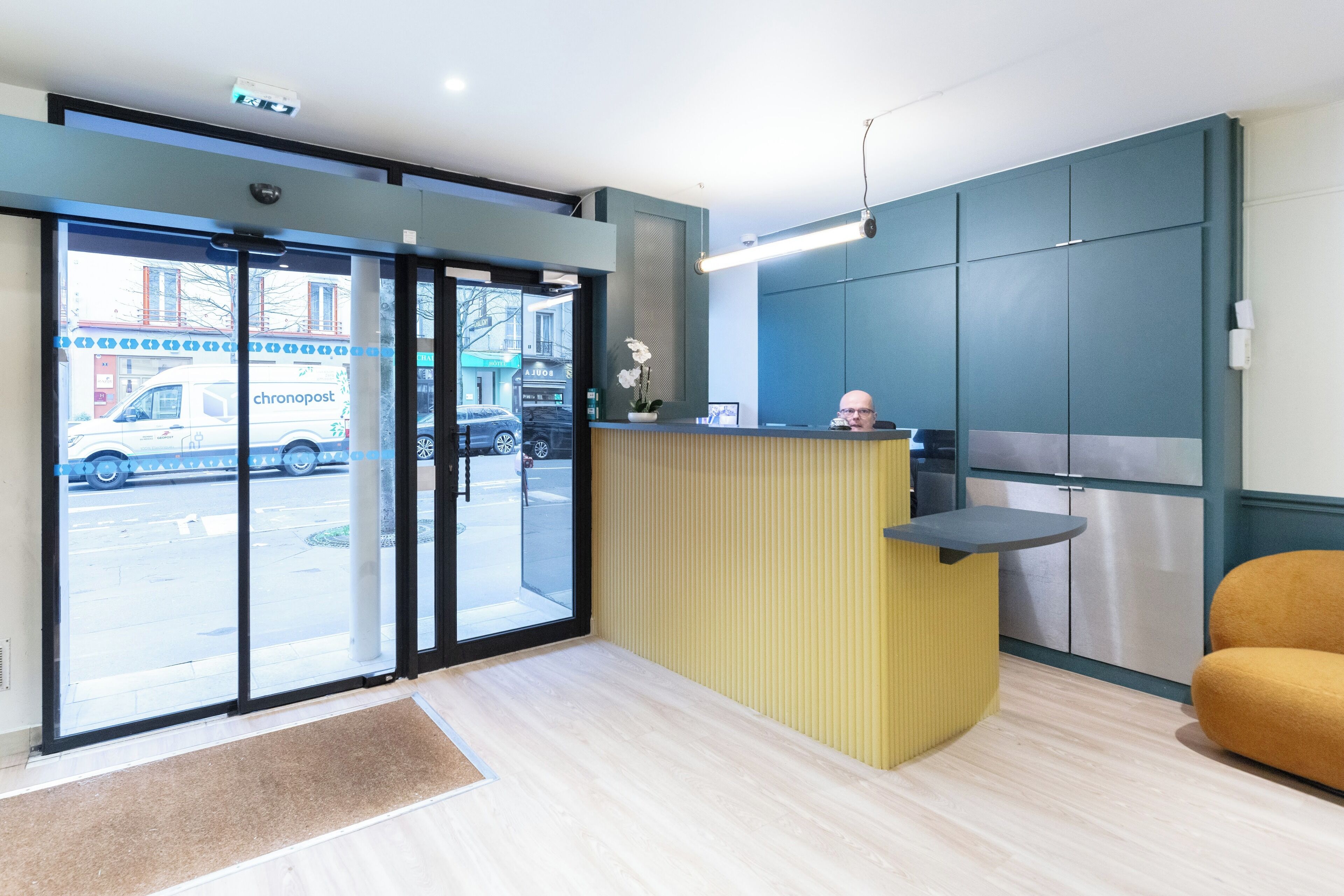 A reception area with a counter, a seating area, and a view of the street outside.