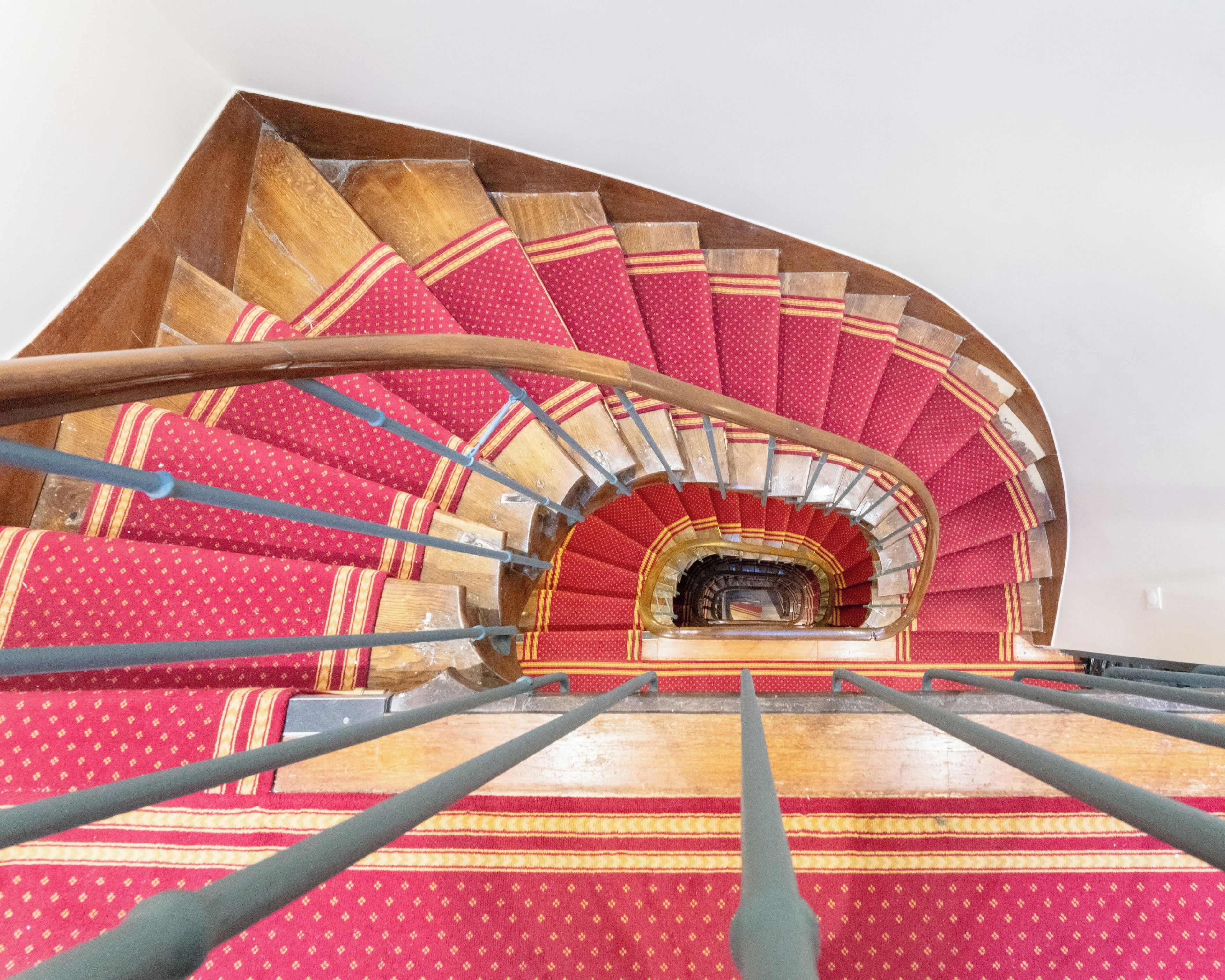 Una escalera de caracol con escalones de diseño rojo y barandilla de madera.