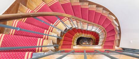 Una escalera de caracol con escalones de diseño rojo y barandilla de madera.