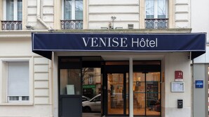 The exterior of the VENISE HOTEL with a prominent entrance, a visible car in the driveway, and a sign indicating the hotel's location. - Hotel De Venise (Paris)