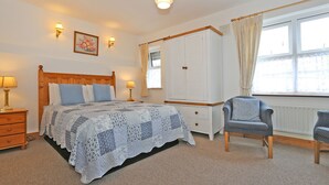 Un dormitorio con cama de madera, dos mesitas de noche con lámparas, un armario y una ventana con cortinas.