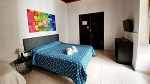 A bedroom with a bed, a wall-mounted TV, a door, and a colorful artwork on the wall. - Arc House Cordoba (Córdoba)
