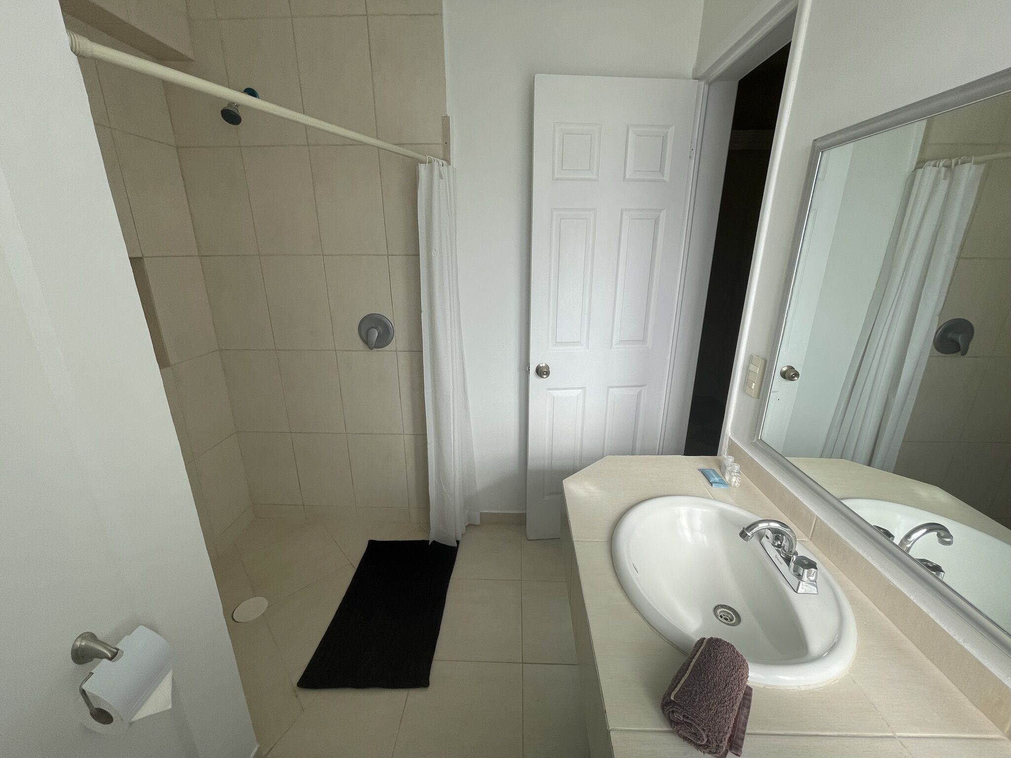 Een badkamer met douche, toilet, wastafel en spiegel.